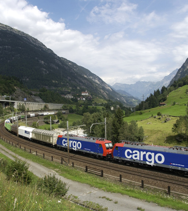 Ein SBB-Cargo-Güterzug fährt durch eine grüne Landschaft, doch der Himmel ist bewölkt